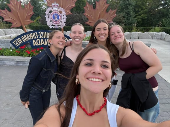 Martina y sus amigas de intercambio frente al cartel de bienvenida a Prince Edward County, Canadá