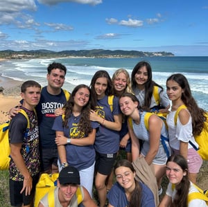 Grupo de jóvenes con mochilas amarillas de InterWay sonriendo en la costa de Asturias frente al mar